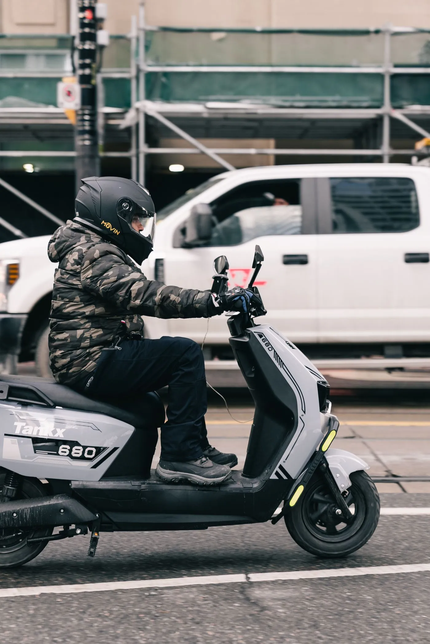 A rider on an electric scooter moving through city traffic.