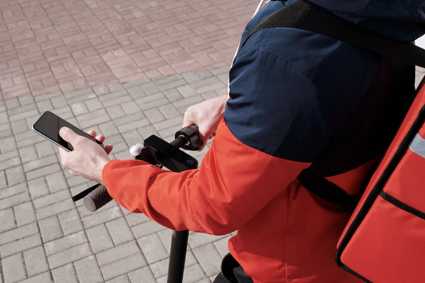 A delivery rider checking a route on a phone at the handlebars.